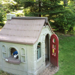 A little tikes play house in the middle of a yard.